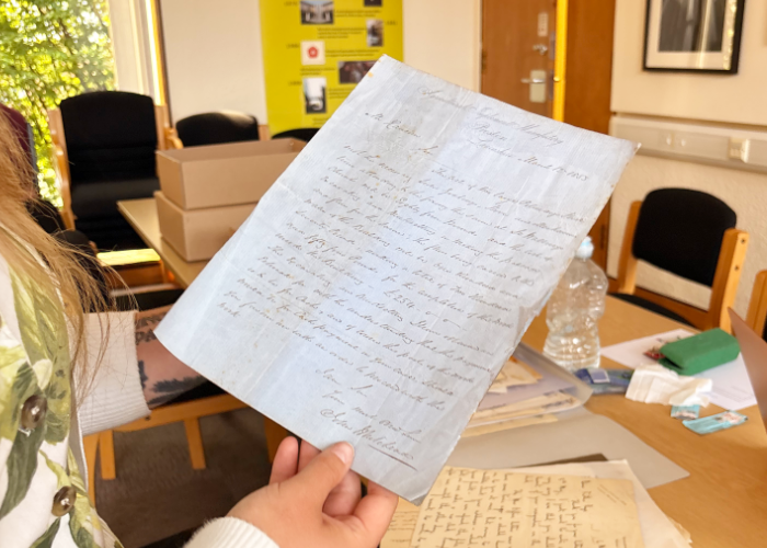 A researcher holding an archival handwritten document from 1853 written in elegant cursive script.