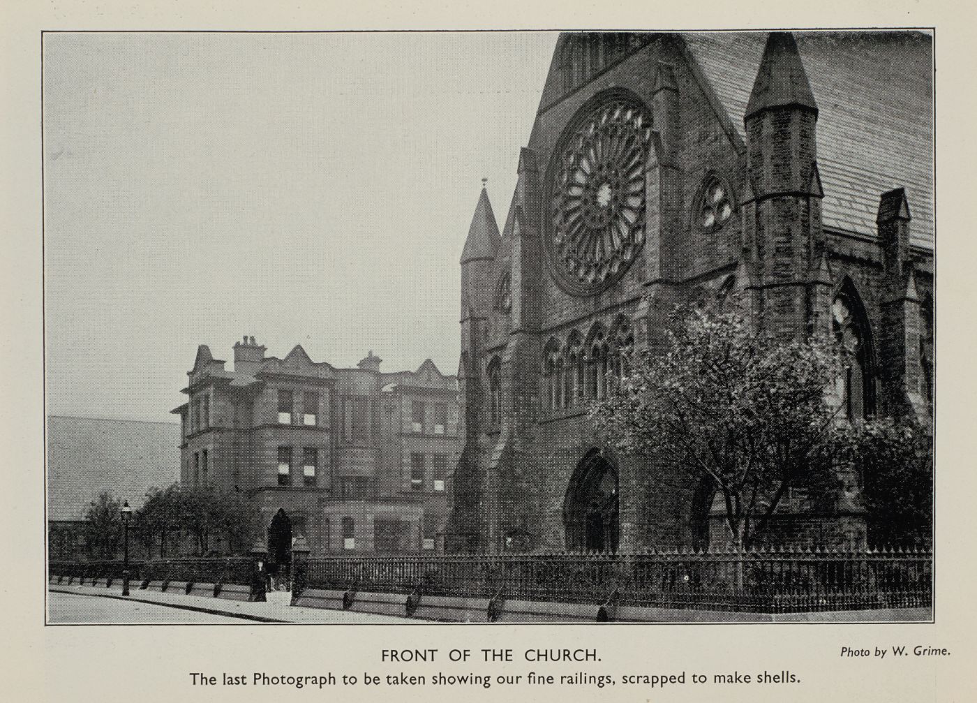 Photograph of St Walburge's west front and rose window with its original iron railings, captioned "Front of the Church. The last photograph to be taken showing our fine railings, scrapped to make shells." Photo by W. Grime.