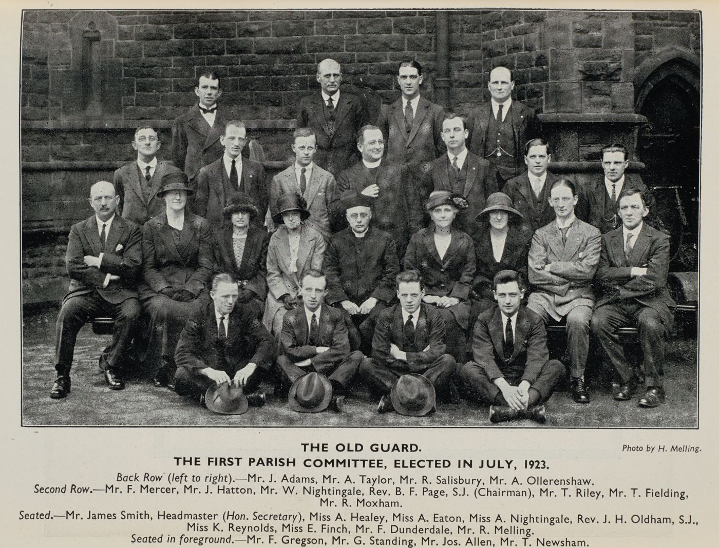 Group photograph of the first parish committee, elected July 1923, arranged in four rows outside the church, each member named in the printed caption below.