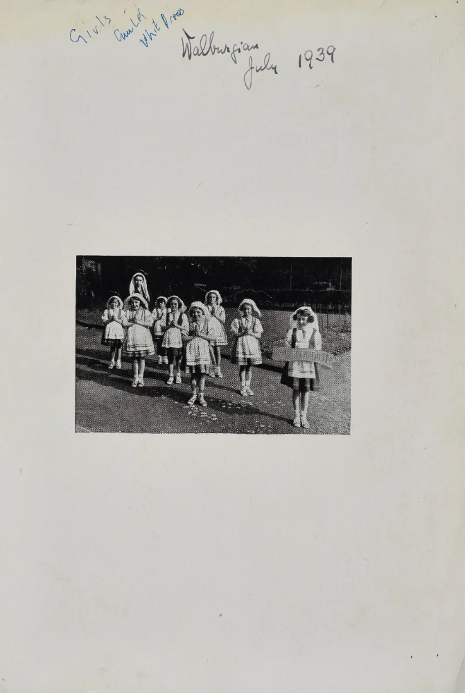 Girls in white veils and dresses walk in procession with hands joined in prayer, captioned "Walburgian, July 1939."