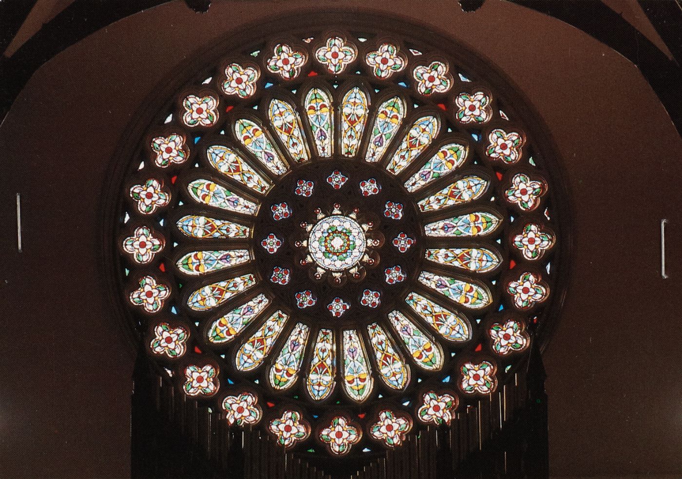 Colour photograph of St Walburge's rose window seen from inside the church, its stained glass petals lit from behind against the dark stone tracery.