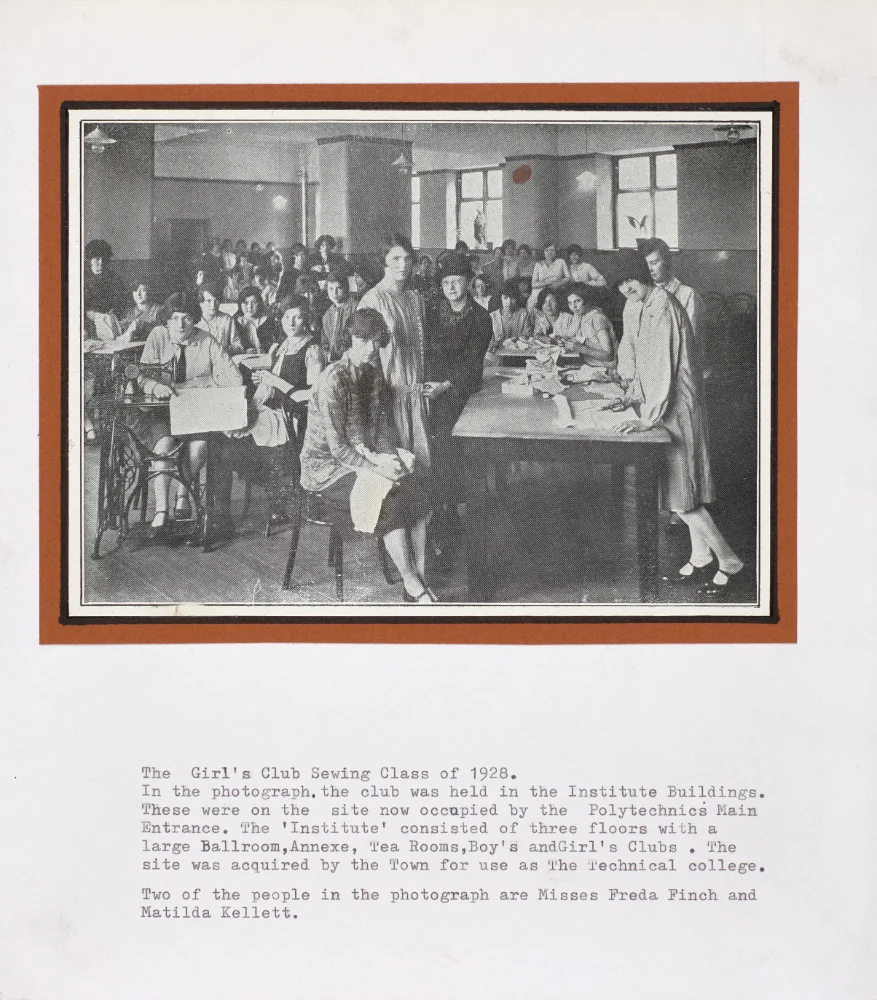 Photograph of the Girls' Club sewing class of 1928 at the Institute Buildings, girls seated at sewing machines and tables, printed caption naming Freda Finch and Matilda Kellett among those pictured.