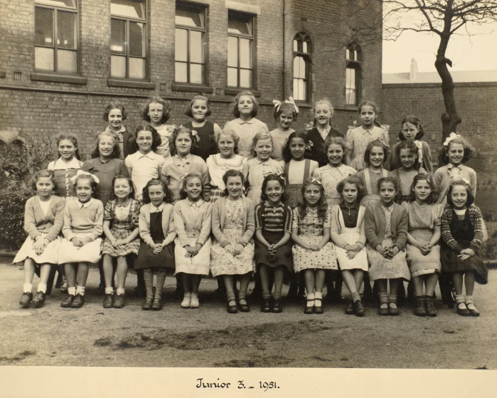 Girls of Junior 3 gather in rows in the schoolyard for a class photograph, captioned "Junior 3 – 1951."