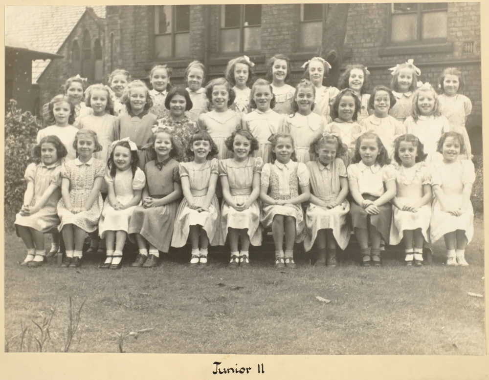 Girls of Junior II gather on the grass in tiered rows for a class photograph, captioned "Junior II."