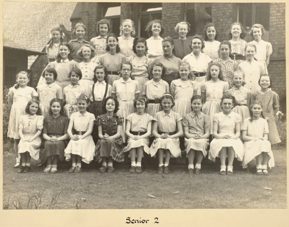 Girls of Senior 2 gather on the grass in tiered rows for a class photograph, captioned "Senior 2."
