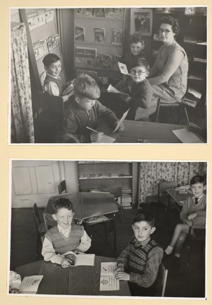 A teacher sits with infant pupils reading picture books beside a bookcase in the upper photograph; below, boys sit reading and writing at desks.