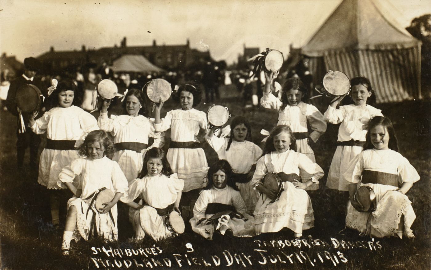 Girls in white dresses with dark sashes hold tambourines aloft, captioned "St Walburge's Tambourine Dancers, Maudland Field Day, July 19, 1913," a striped marquee behind.